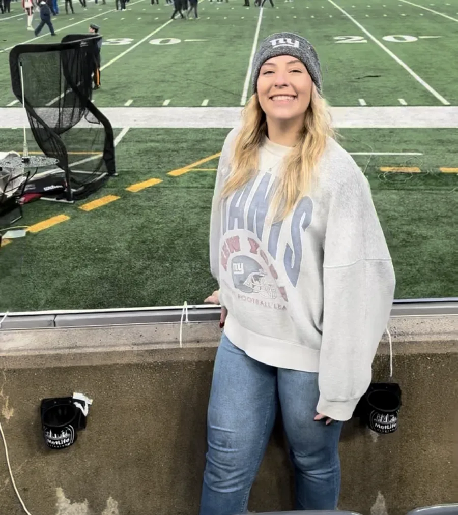 Amber Fugedi field-side at MetLife Stadium in a vintage New York Giants sweatshirt.